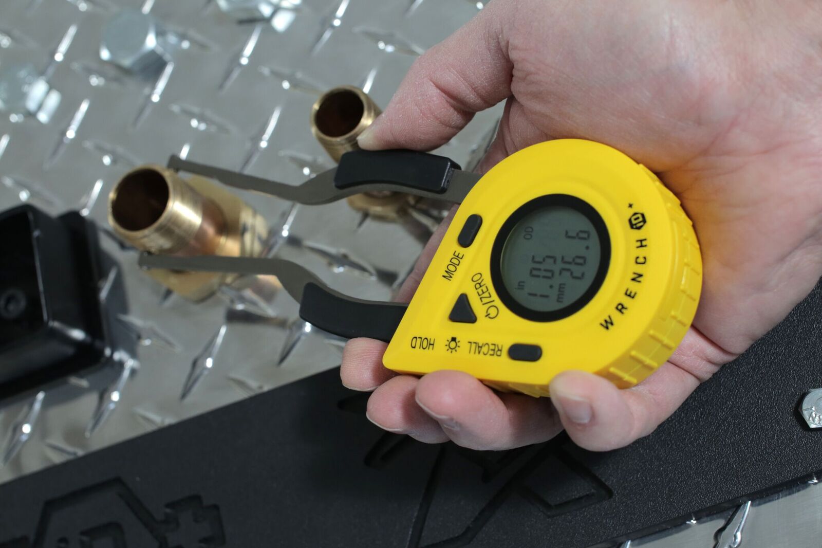 The WrenchID being used to measure the size of a pipe fitting.